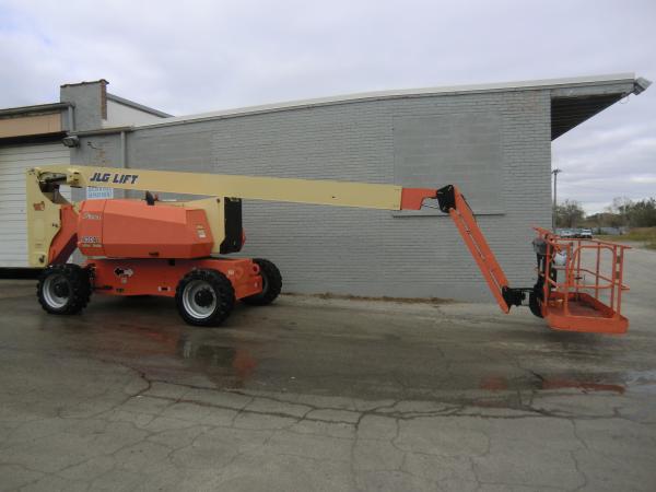 A JLG Lift crane is stationed outside of grey brick building in the parking lot.