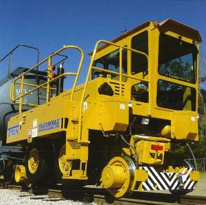 A piece of yellow heavy machinery that is stationed on top of a railroad that seems to be shunting a railcar.