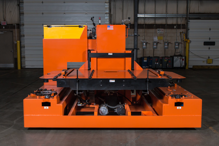 A large orange piece of heavy machinery sits in an empty warehouse.