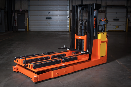 An orange piece of heavy machinery that is located inside of a warehouse.