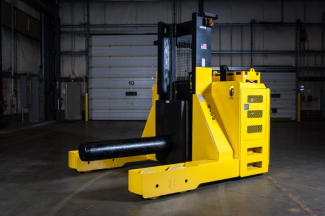 A large piece of material handling equipment that is stationed in an empty warehouse.