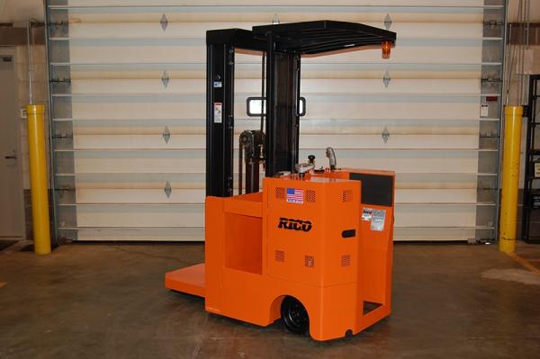 An orange Rico forklift that is stationed inside of a warehouse.