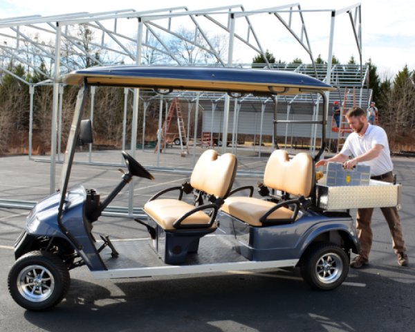 A man is loading boxes into the back of a blue Star electric vehicle that is parked outside.