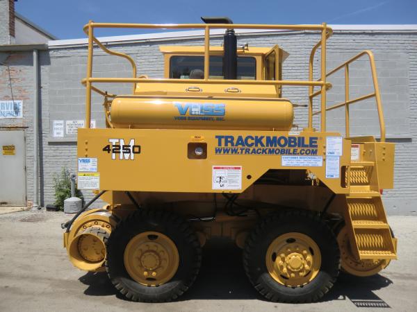 A piece of yellow Voss heavy equipment that is parked outside in front of a warehouse.